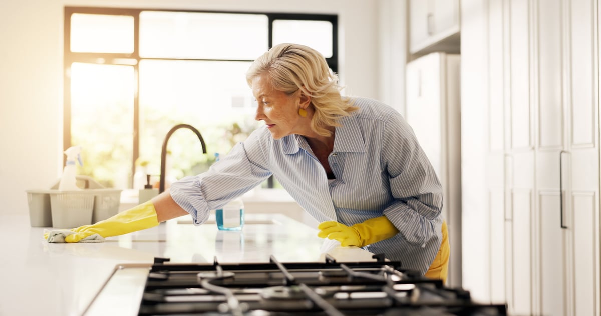 A professional cleaner wiping down a kitchen counter with a cloth